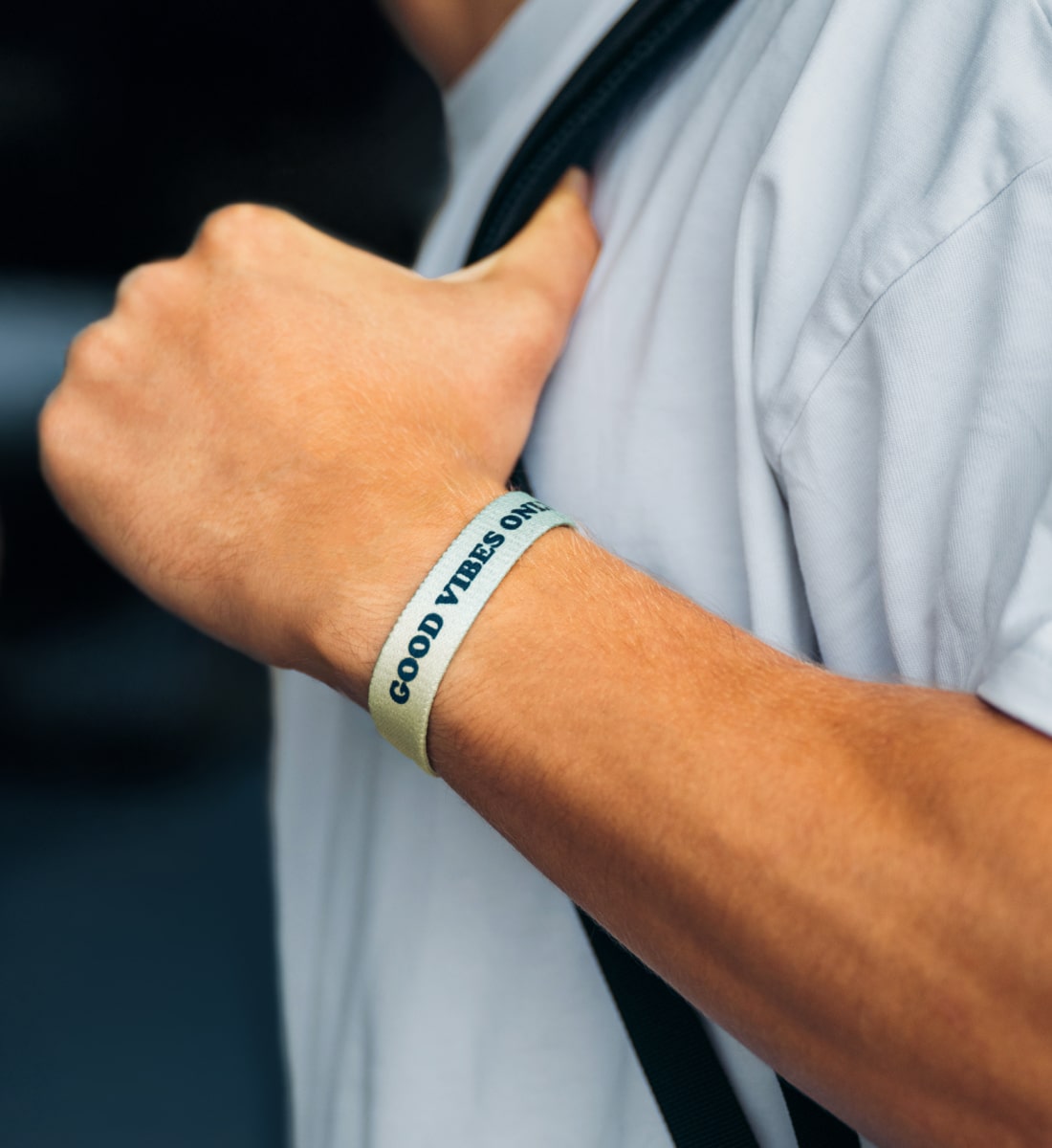good vibes only Armband, elastisches Armband mit Schriftzug am Handgenk eines jungen Mannes, der einen Rucksack hält