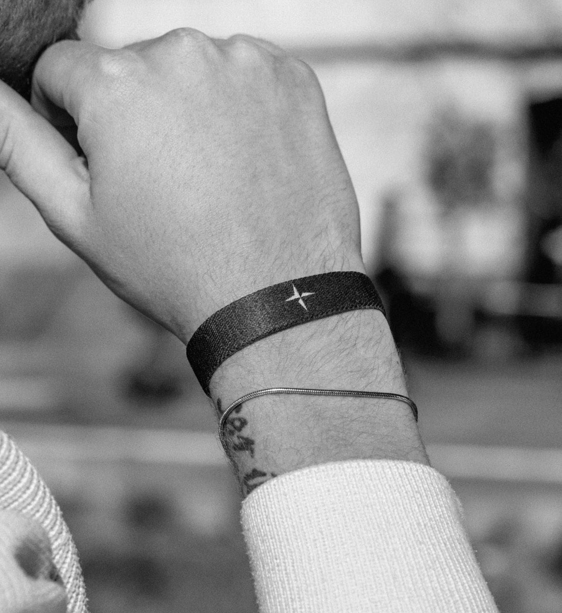 Elastisches Armband von Goodbands aus der "humble" Kollektion in schwarz weiß mit dezentem Kompassnadel-Symbol, getragen von einem Mann