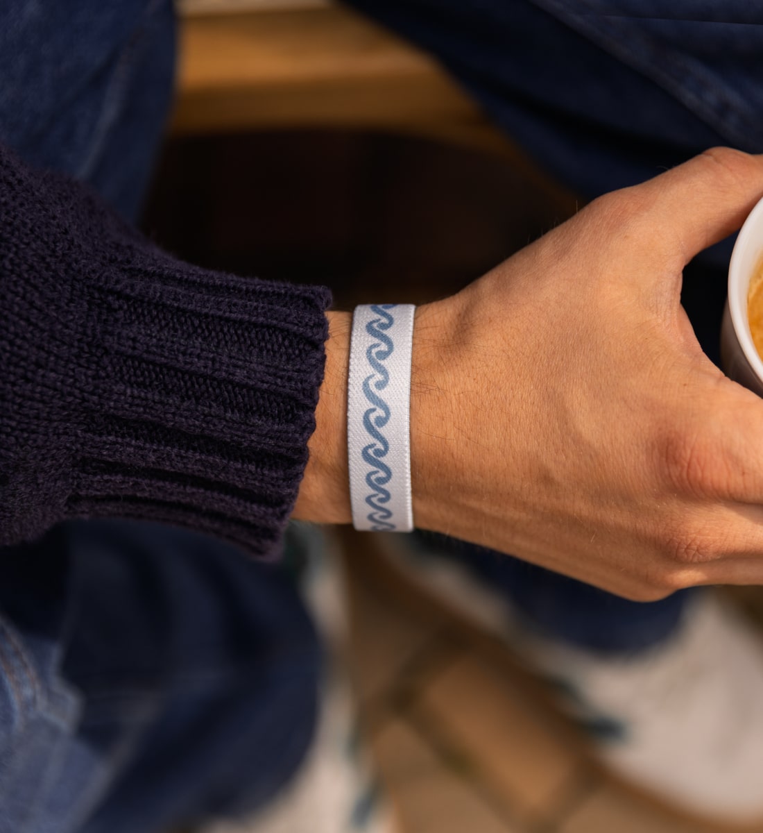 Elastisches Stoff-Armband von Goodbands aus der "airwaves" Kollektion mit skandinavischem Muster in grau-blau, am Handgelenk von einem Mann