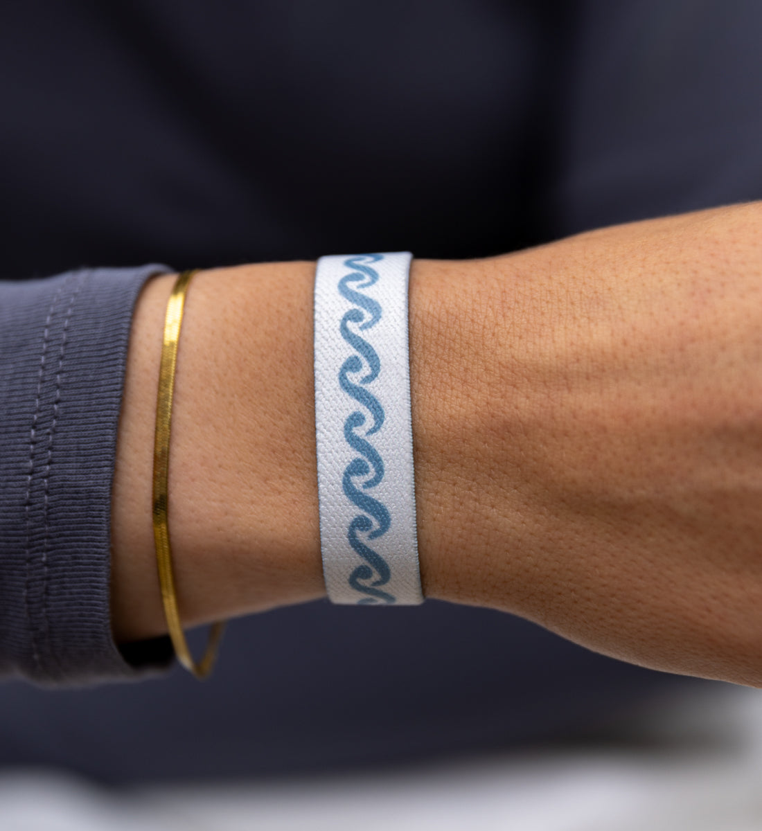 Modernes Armband von Goodbands aus der "airwaves" Kollektion mit skandinavischem Muster in grau-blau, am Handgelenk von einer jungen Frau