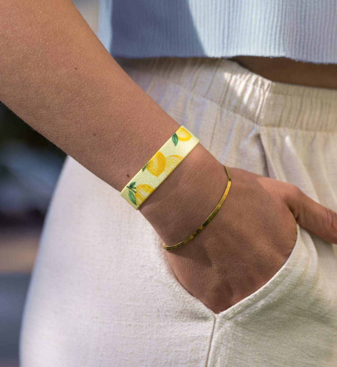 Elastisches Armband von Goodbands aus der "easy peasy" Kollektion mit gelbem Zitronenmuster, am Handgelenk von einer jungen Frau getragen