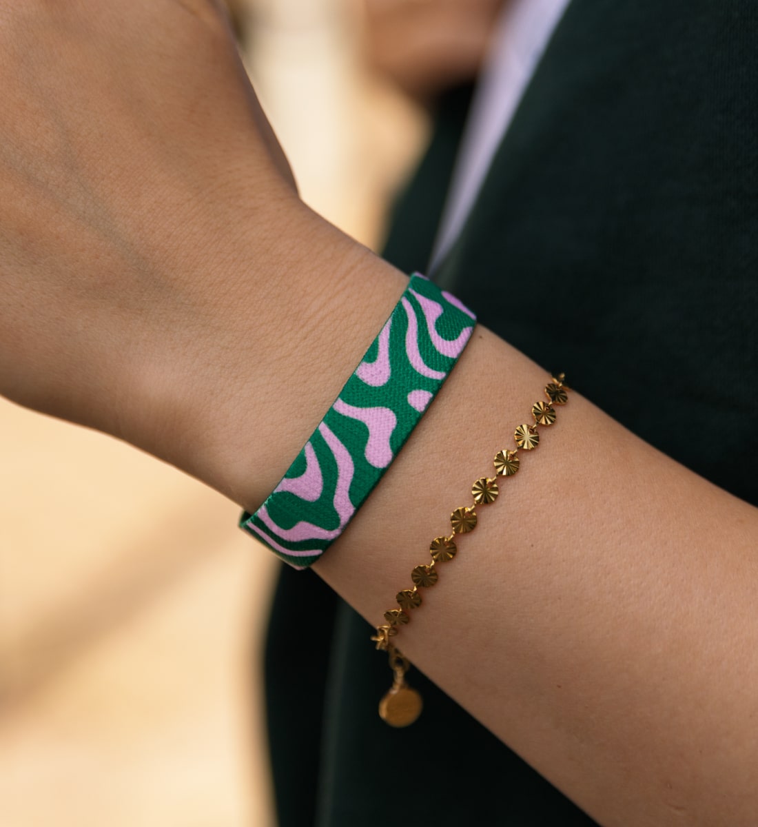 Elastisches Armband von Goodbands aus der "good energy" Kollektion mit organischen Rundungen als Muster in pink & grün, am Handgelenk von einer jungen Frau getragen