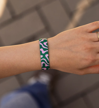 Modernes Armband von Goodbands aus der "good energy" Kollektion mit organischen Rundungen als Muster in pink & grün, am Handgelenk von einer jungen Frau in der POV Ansicht